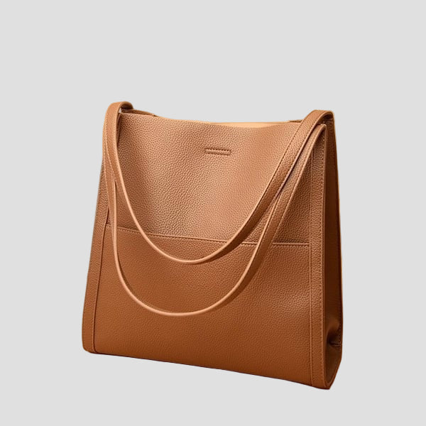 An Audrey Dublin shoulder bag in a natural colour, styled with a gold chain strap, sitting on a white background.